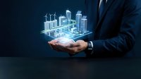 Businessman in dark suit holding glowing holographic cityscape with wind turbines and skyscrapers, representing sustainable urban development and smart city technology solutions.