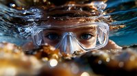Close up view of eyes wearing protective swimming goggles underwater with sunlight creating golden reflections and bubbles in blue water. Dramatic sports action shot.