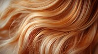 Flowing golden blonde hair with natural highlights and soft waves creating elegant texture and movement. Ideal for beauty and haircare advertising.