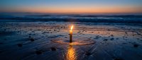Serene beach sunset with golden light reflecting on wet sand and gentle waves during twilight hour creating peaceful coastal atmosphere.