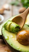Fresh ripe avocado half with wooden spoon scooping creamy green flesh for healthy cooking and nutrition concepts.