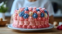 Colorful birthday cake with pink buttercream frosting and decorative piped rosettes in blue, yellow and coral colors on white plate in kitchen setting.
