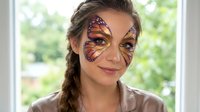Young woman with professional monarch butterfly face paint design for costume party or festival celebration.