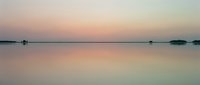 Serene dawn landscape with calm water reflecting soft pastel sky, distant islands and boats creating minimalist composition for nature, travel and meditation projects.