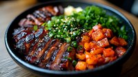 Grilled teriyaki beef slices with glazed carrots and fresh chopped green onions on black plate, garnished with sesame seeds, close up view of Asian cuisine.