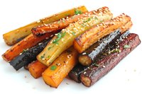 Roasted rainbow carrots garnished with fresh herbs and seasonings on white background, colorful grilled vegetable side dish for healthy eating and cooking.