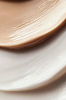 Smooth flowing curves in beige and white create elegant abstract background with soft gradient transitions and delicate textured streaks for luxury branding designs.