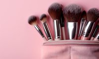 Professional makeup brushes with soft bristles arranged in pink cosmetic bag on pastel background, beauty and cosmetics concept for social media and blogs.