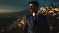 Professional businessman in pinstripe suit standing on mountain cliff during golden hour sunset, corporate executive outdoor portrait for business success concepts.