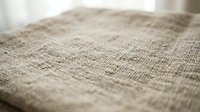 Natural beige linen fabric texture with visible weave pattern and soft focus depth of field for textile and interior design projects.