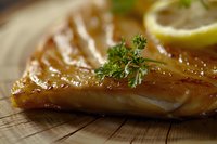 Grilled salmon fillet with fresh thyme and lemon slice on wooden cutting board, glazed with honey marinade, macro food photography with selective focus.