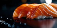 Fresh salmon nigiri sushi pieces arranged on dark surface with selective focus and dramatic lighting, showcasing vibrant orange fish texture and white rice.