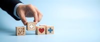 Healthcare professional selecting medical insurance and wellness benefits with wooden blocks showing health symbols.