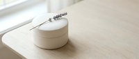 Minimalist wooden cosmetic jar with lavender sprig on natural wood surface. Clean spa product packaging for organic skincare and beauty treatments.