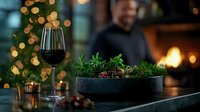 Elegant dining scene with red wine glass and gourmet dish in cast iron pan against blurred festive lights and cozy restaurant atmosphere. Professional food photography.
