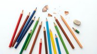 Sharpened colored pencils arranged in rows with wood shavings and sharpener on white background for art, design, and creative projects.