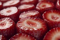Fresh sliced strawberries in macro view showing detailed texture and natural patterns of red fruit flesh, seeds, and inner structure. For food industry and packaging.