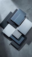 Stack of modern material samples in gray, white and blue tones on concrete surface with dramatic shadows for interior design and architecture projects.