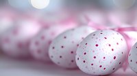 White Easter eggs with pink polka dots and ribbon on soft pastel background for spring holiday celebration and festive decoration projects.