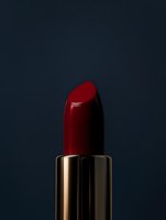 Luxury red lipstick with golden tube on dark background for cosmetics and beauty product advertising campaigns.