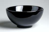 Elegant black ceramic bowl with glossy finish on light gray background, minimalist tableware design for modern dining and food presentation photography.