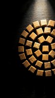 Neatly stacked firewood logs arranged in circular pattern with dramatic lighting on dark textured wall background for heating and home decor concepts.