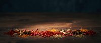 Scattered spices and dried herbs on dark wooden surface with warm golden lighting, suitable for food photography, culinary blogs, and recipe content.