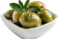 Green olives stuffed with cheese in white ceramic bowl with olive oil, herbs and spices. Mediterranean appetizer close up on white background.