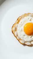Golden fried egg with crispy edges and bright yellow yolk on clean white background for breakfast and cooking concepts.