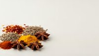 Aromatic spices including star anise, turmeric, paprika and fennel seeds arranged on neutral background for culinary and cooking projects.
