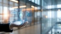 Businessman hand holding digital security icons including umbrella, shield, and data storage in modern office environment with blurred background.