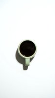 Green ceramic coffee mug with black coffee viewed from above on white background isolated for design use in branding and lifestyle projects.