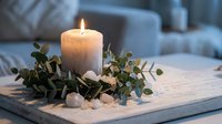 Lit white candle surrounded by eucalyptus leaves on wooden tray creates cozy bedroom atmosphere for relaxation and home decor styling.
