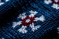 Closeup of knitted fabric with red and white snowflake pattern on dark blue background, suitable for winter textile and holiday design projects.