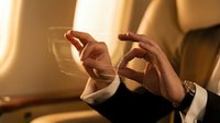 Business professional using smartphone on luxury private jet during flight with warm golden lighting creating elegant travel atmosphere.