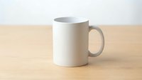 Plain white ceramic mug on a wooden table with a light background, mockup for custom print design, branding, and merchandise presentation.