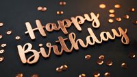 Rose gold Happy Birthday lettering on dark background with shiny confetti, elegant celebration concept for greeting cards and party decor.