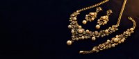 Elegant gold floral jewelry set with pearls, including necklace, bracelet, and earrings on dark background, luxury fashion accessory.