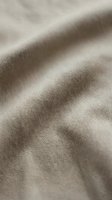 Closeup of natural linen fabric with diagonal folds and soft shadows, showcasing woven texture and neutral beige tones suitable for textile, fashion, and interior design projects.