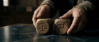 Hands protecting wooden blocks with justice scales and gavel symbols on dark surface representing legal protection and law enforcement concepts.