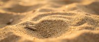Close-up of golden sand texture with natural ripples and waves, suitable for backgrounds, nature themes, and beach-related design projects.
