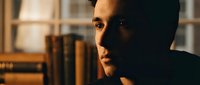 Young professional man in contemplative mood with warm lighting in modern office or library setting for business and lifestyle concepts.