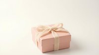 Small pink gift box with cream ribbon bow on white background for holidays, birthdays, celebrations and special occasions.
