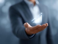 Professional businessman in suit holding glowing growth chart hologram in palm, demonstrating business success and financial performance analytics.