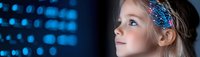 Young blonde girl with blue butterfly hairpiece gazing upward against blurred blue bokeh lights background, expressing wonder and curiosity in panoramic composition.