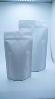 Two silver metallic stand-up pouches with zip closure displayed in modern white studio setting for product packaging and branding applications.