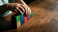 Hands arranging colorful wooden blocks on table representing business growth strategy planning and development concepts for presentations.