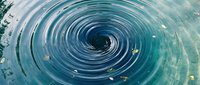 Mesmerizing water vortex with spiral ripples creating hypnotic circular patterns in turquoise blue liquid surface for abstract backgrounds and motion concepts.