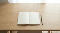Open notebook with blank pages and pen on wooden desk surface, ready for writing, planning, or creative work.