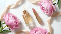 Luxury cosmetics with pink peonies and silk ribbon on white background. Premium beauty products flatlay for skincare and makeup branding campaigns.